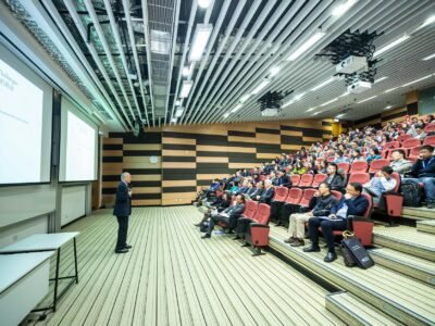 man standing in front of people sitting on red chairs